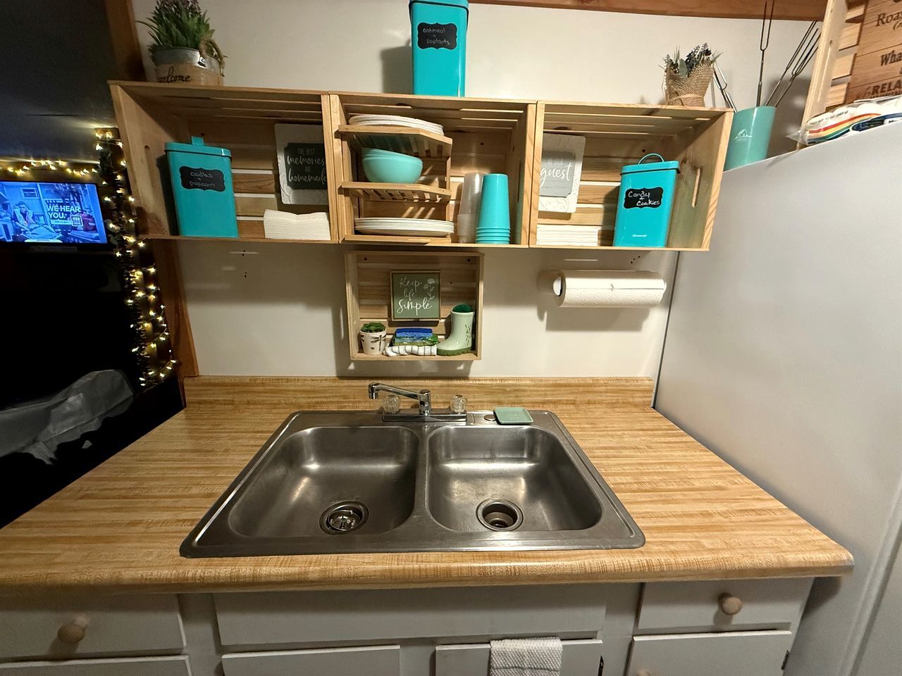 A kitchen with two stainless steel sinks, wooden countertops, and teal storage containers.