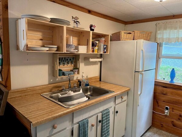 A compact kitchen with wooden cabinets, a sink, and a refrigerator.