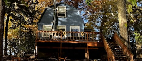 Eine Hütte mit einer Holzterrasse, einer Treppe und einem Fenster.