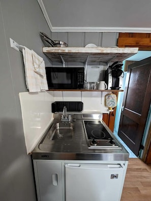 A compact kitchenette with a sink, stove, and microwave. - Bright Seaside Cottage with Panoramic Views in North Truro, Massachusetts (North Truro)