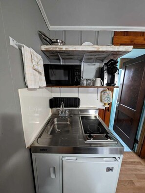 A compact kitchenette with a sink, stove, and microwave. - Bright Seaside Cottage with Panoramic Views in North Truro, Massachusetts (North Truro)