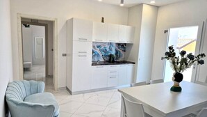 A modern kitchen with white cabinets, a marble backsplash, and a dining area with a white table and chairs. - At 211 Rooms Guest House (Room No. 5) (Pizzo)