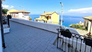 A rooftop terrace with a view of the sea, a paved walkway, and a railing with potted plants. - At 211 Rooms Guest House (Room No. 5) (Pizzo)