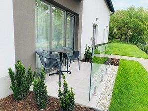 A modern outdoor seating area with a glass balustrade, a small table, and two chairs. - Exclusive apartment in the center of Tihany with a two-person hot tub. (Tihany)