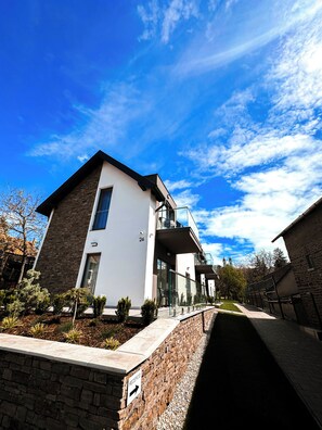 A modern two-story building with a stone facade, a balcony, and a clear sky. - Exclusive apartment in the center of Tihany with a two-person hot tub. (Tihany)