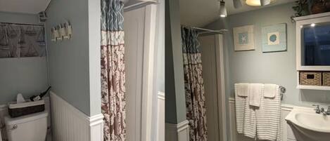 A bathroom with a toilet, shower curtain, sink, and towel rack.