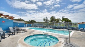A swimming pool with lounge chairs, a hot tub, and a fenced area. - Ocean & Jetty Views | Pool & Hot tub | #920 (Westport)