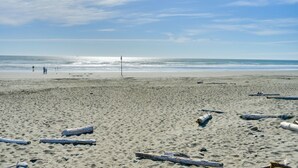 A beach with sand, scattered logs, and a clear sky. - Ocean & Jetty Views | Pool & Hot tub | #920 (Westport)