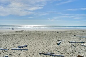 A beach with sand, scattered logs, and a clear sky. - Ocean & Jetty Views | Pool & Hot tub | #920 (Westport)