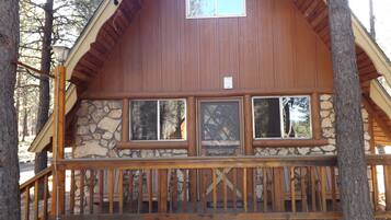 Une cabane avec des fondations en pierre, un revêtement extérieur en bois et un balcon doté d’une balustrade.