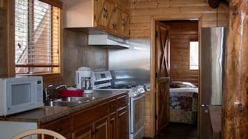 Una cocina con armarios de madera, estufa de acero inoxidable, microondas y pileta.