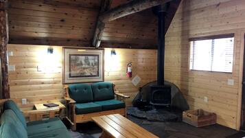L’intérieur d’un chalet accueillant, avec un canapé, une table en bois, une cheminée et un tableau encadré au mur.
