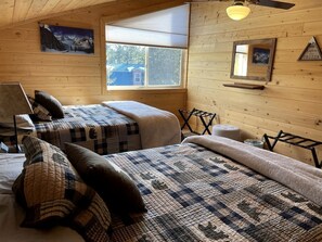 Eine Hütte mit zwei Betten, einem Fenster, einem Deckenventilator und einem Bild an der Wand.