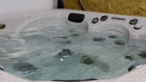 A hot tub with clear water, a control panel, and a wooden wall in the background. - Amazing Spacious Barn near Yellowstone National Park, Idaho (Island Park)