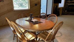 A round wooden dining table with six chairs, a coffee maker, and a placemat. - Amazing Spacious Barn near Yellowstone National Park, Idaho (Island Park)