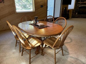 Una mesa de comedor redonda de madera con seis sillas, una cafetera y un mantel individual.