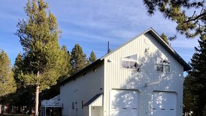 A white building with two garage doors, a covered porch, and a dirt ground. - Amazing Spacious Barn near Yellowstone National Park, Idaho (Island Park)