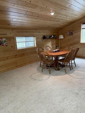 Una habitación con paneles de madera, una mesa redonda y sillas, una ventana y una lámpara.