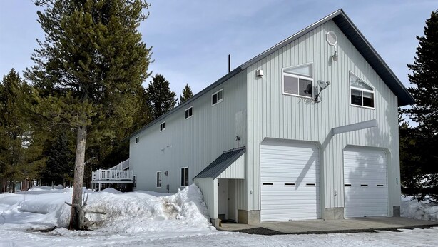 A white building with two garage doors, a ramp, and a snow-covered ground. - Amazing Spacious Barn near Yellowstone National Park, Idaho (Island Park)