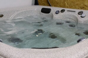 Ein Whirlpool mit klarem Wasser, einer Steuerung und einer Holzverkleidung im Hintergrund.