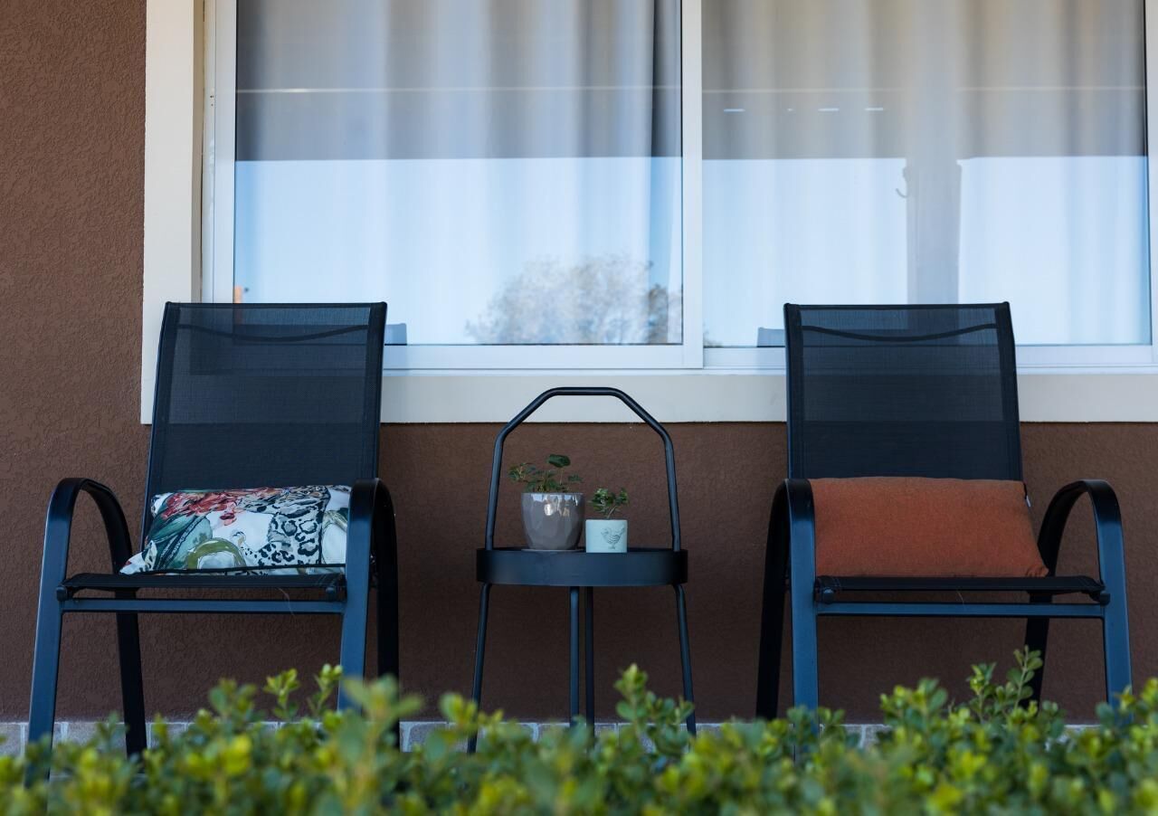 Two chairs with cushions, a small table with a potted plant, and a window with curtains.
