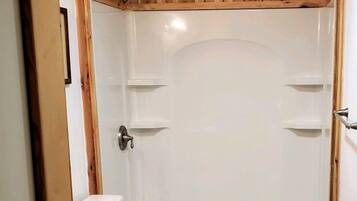 A bathroom with a wooden vanity, a white sink, and a shower enclosure.