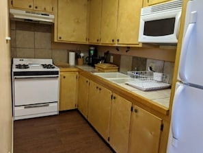 Una cocina con armarios de madera, estufa blanca, microondas y refrigerador.