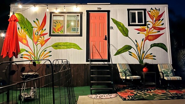 Uma casa com porta vermelha, janela e escadaria que leva à entrada.