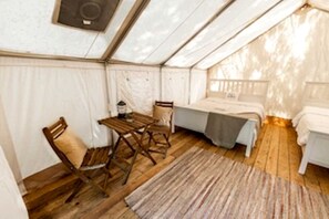 A tent with a bed, a table, and chairs.