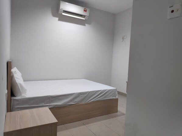 A single bed with a wooden headboard, a white mattress, and a wall-mounted air conditioner.