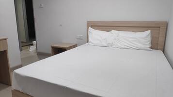 A neatly made bed with a wooden headboard, a bedside table, and a small nightstand.