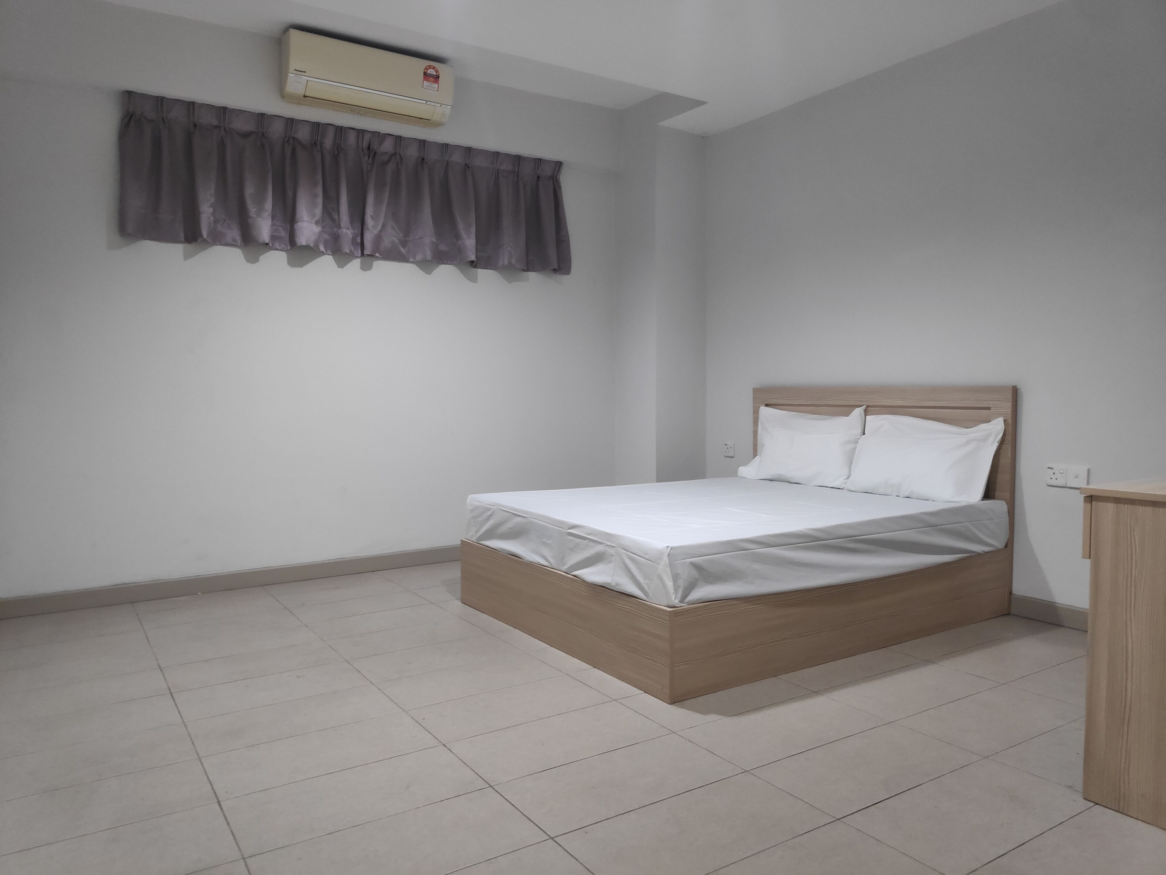A bedroom with a bed, a curtain, an air conditioning unit, and a tiled floor.