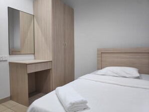 A bedroom with a bed, a wooden wardrobe, a mirror, and a bedside table.