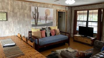 Una sala de estar amoblada con un sofá, una mesa de madera, un televisor y un cuadro en la pared.