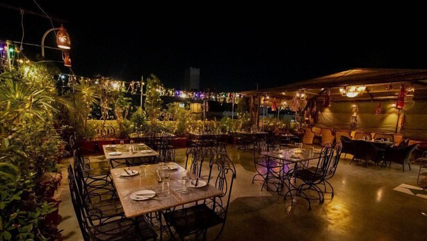 An outdoor restaurant with tables and chairs, surrounded by potted plants and string lights. - Hotel Pearl Heritage (Jaipur)