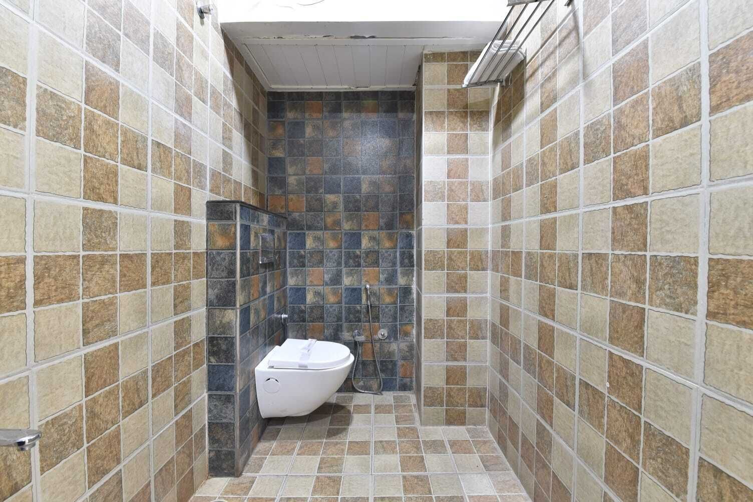 A bathroom with tiled walls and floor, a toilet, and a shower area.
