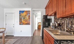 Una cocina con armarios de madera, un refrigerador negro y un salpicadero de azulejos.