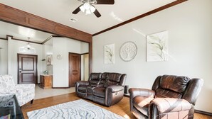 A spacious living room with a ceiling fan, a fireplace, and a large mirror.