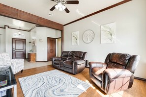A spacious living room with a ceiling fan, a fireplace, and a large mirror.
