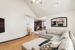 A modern living room with a sectional sofa, a wooden coffee table, and a kitchen in the background.