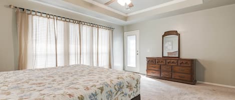 Un dormitorio con cama, cómoda, ventilador de techo y puerta.