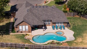 A residential property with a large backyard, a swimming pool, and a covered patio area.