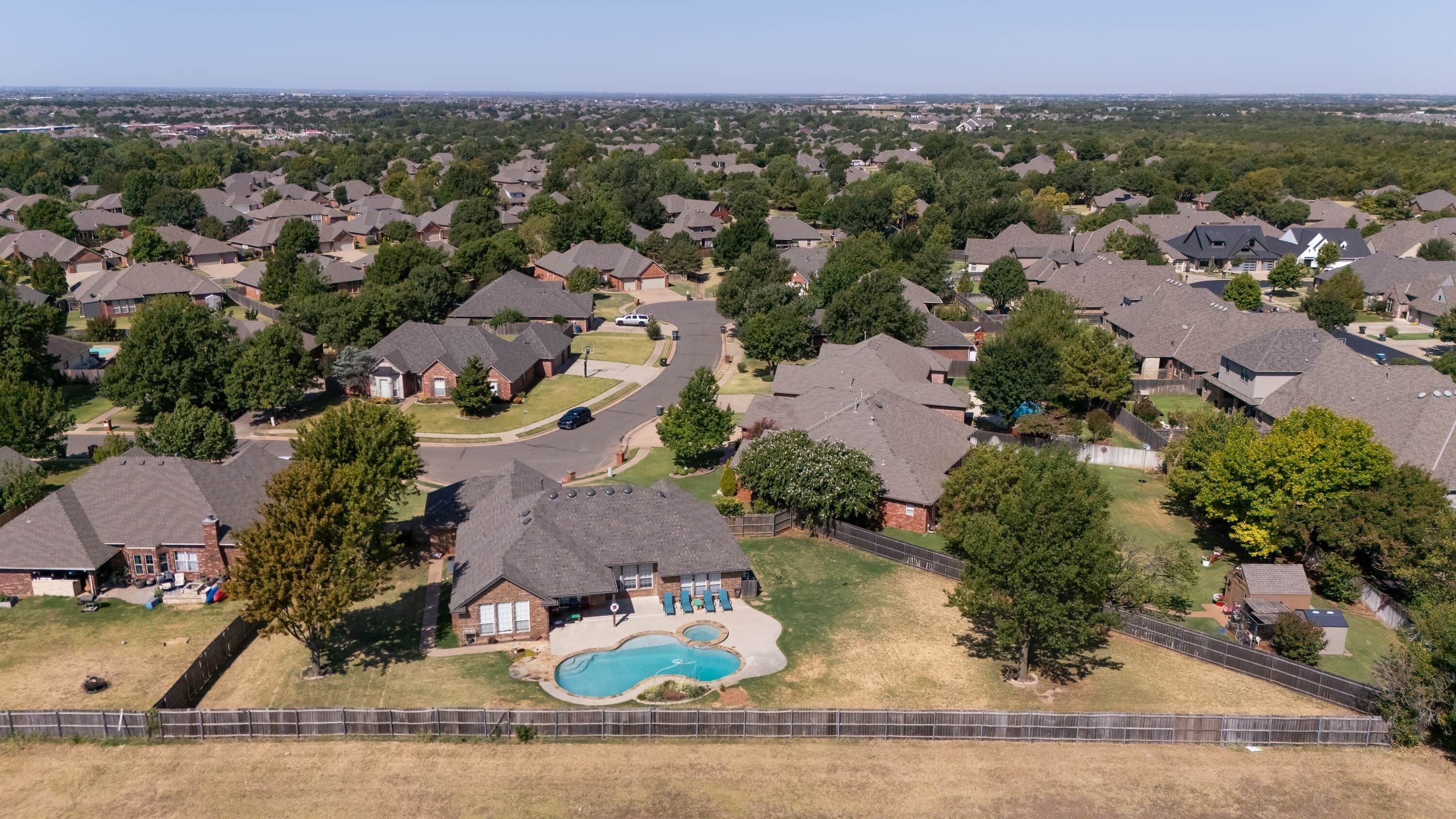 A residential area with houses, a swimming pool, and a fenced yard.