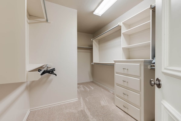 A walk-in closet with open shelving, a hanging rod, and a set of drawers.