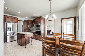 A kitchen with dark wooden cabinets, stainless steel appliances, a granite countertop, and a dining area with wooden chairs and a table.