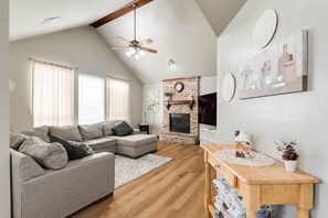 A modern living room with a sectional sofa, a fireplace, and a wooden dining table.