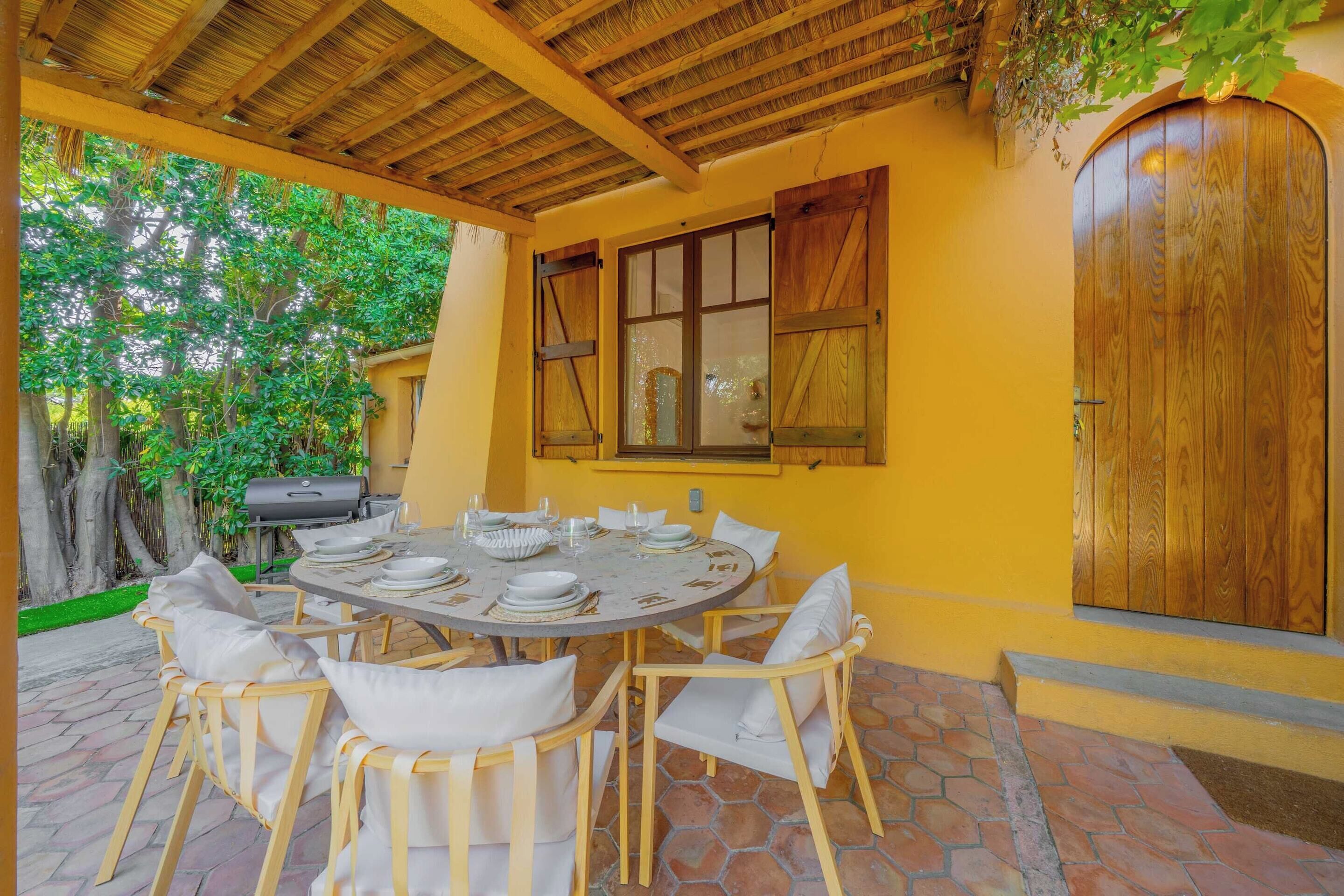 An outdoor dining area with a round table, chairs, and a grill.