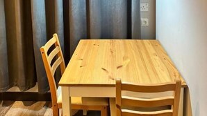 Un comedor con una mesa y sillas de madera, una lámpara colgante y un telón de fondo.