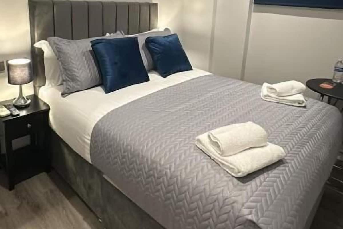 A modern bedroom with a bed, nightstands, and a window.