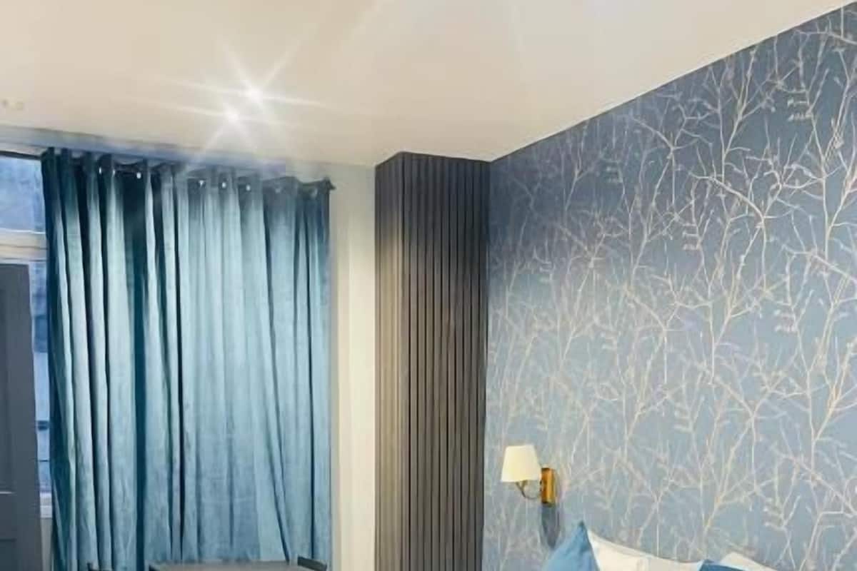 A modern hotel room with a large bed, a desk, and a view of the outdoors.